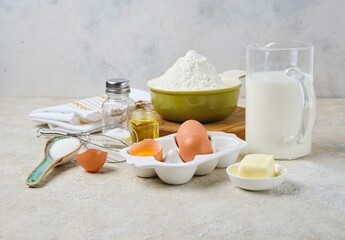 Step-by-step preparation of thin pancakes or crepes on a light background. Prepared ingredients for cooking crepes.