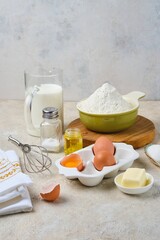 Step-by-step preparation of thin pancakes or crepes on a light background. Prepared ingredients for cooking crepes.