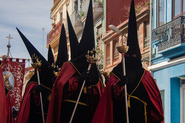 Penitents walk solemnly, dressed in traditional robes and tall hoods, through the streets during the Holy Week procession