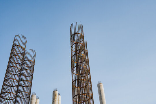 A large collection of sturdy metal pipes stands against a vibrant blue sky, showcasing an intricate display of engineering and industrial design in a highrise environment