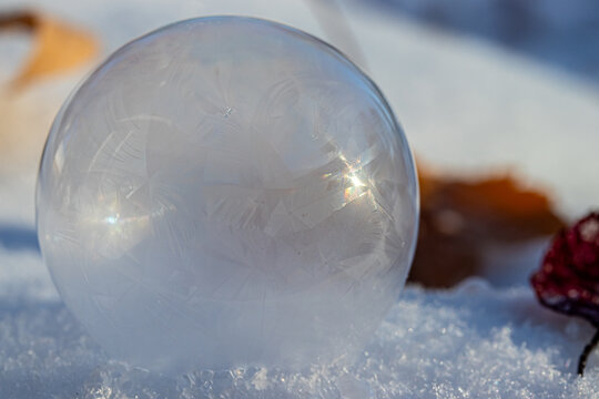 Macro Photo of a Frozen Soap Bubble forming Geometric Ice Crystals as it sits on snow. 