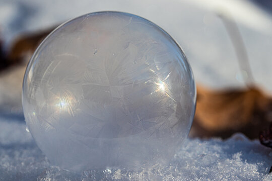 Macro Photo of a Frozen Soap Bubble forming Geometric Ice Crystals as it sits on snow. 