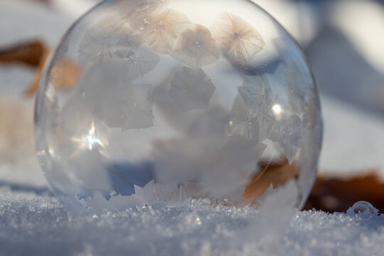 Macro Photo of a Frozen Soap Bubble forming Geometric Ice Crystals as it sits on snow. 
