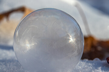 Macro Photo of a Frozen Soap Bubble forming Geometric Ice Crystals as it sits on snow. 