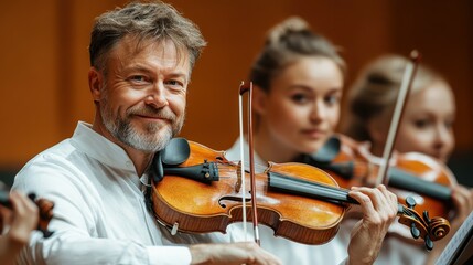 A group of musicians plays string instruments in a concert hall. The male violist smiles while performing, surrounded by focused musicians in elegant attire