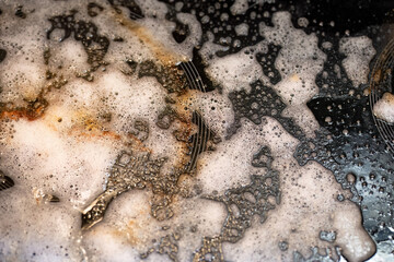 Soap foam and grease on a stovetop during cleaning
