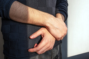 Beautiful male hands, illuminated by sunlight, are folded in a cross on his stomach.