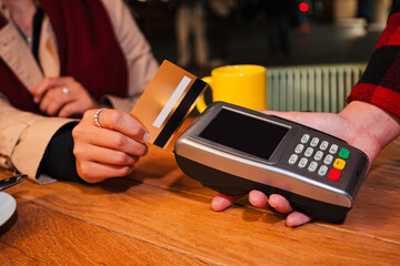 Close up portrait of a unrecognizable customer hand using a credit card for contactless payment on a card reader at a cafe, highlighting modern payment technology, convenience, and shopping