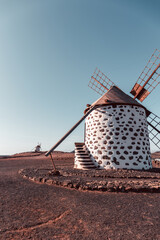 View of the old, typical windmills of Villaverde, Fuerteventura, Canary Islands, with their wooden blades. almost sunset, oblique light, golden hour. Past, vintage feeling.