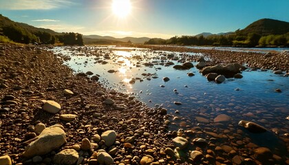 stones along the riverbed with water and mirror sunlight during sunset, light passes through;