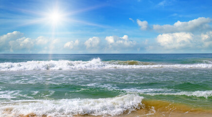 Sea and bright sun on blue cloudy sky.