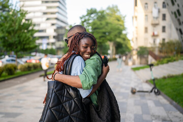 Smiling black wife laugh and hug husband tightly, emotional family reunion outdoors. Joy and love...