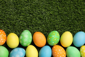 Beautiful decorated Easter eggs on green grass, flat lay. Space for text