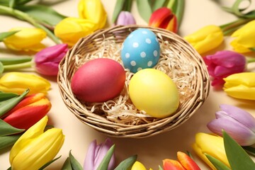 Easter eggs and beautiful tulips on beige background, closeup