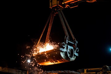 Sparks fly as molten metal is lifted in the heart of a bustling foundry during the night