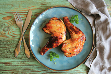 Food background. Grilled chicken leg quarters with crispy golden brown skin, lemon and vegetables for celebration and holiday