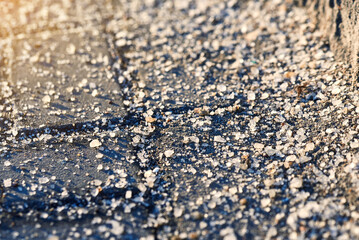 Salt crystals on an asphalt road during winter, ensuring vehicle safety and ice prevention in harsh roadside conditions. Roadside safety measures and deicing treatments for vehicles.