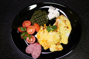 omelette sausage tomatoes pasta pesto and feta on plate breakfast lunch black dishes. High quality 4k footage