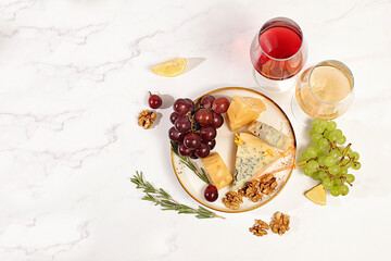 Top view of cheese plate with seasonal wine snacks, still life with gourmet blue cheese, parmesan, grapes, nuts, rosemary and wine. Italian cuisine concept, menu for restaurant and cafe.