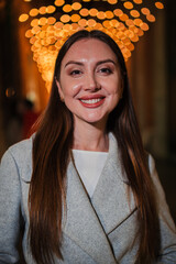 Vertical. Smiling woman with long hair looking directly at the camera, wearing a stylish coat,...