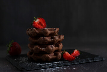 dessert pastry chocolate waffles with strawberries on a dark background