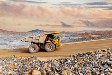 Massive Mining Dump Truck Transporting Ore in Open Pit Mine at Sunset