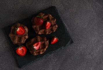 dessert pastry chocolate waffles with strawberries on a dark background