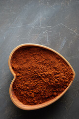 Freshly ground aromatic coffee presented in a beautifully carved wooden heart-shaped bowl.