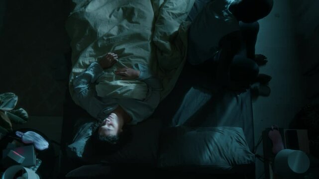 Top view shot of African American man waking up his Caucasian wife at night by sleepwalking in their bedroom