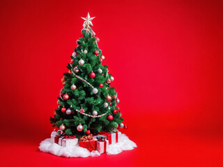 Decorated Christmas tree with gifts on the floor against a vibrant red background