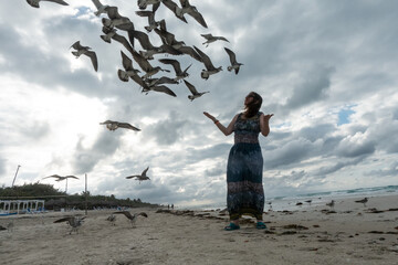 A woman feeds seagulls on the ocean shore