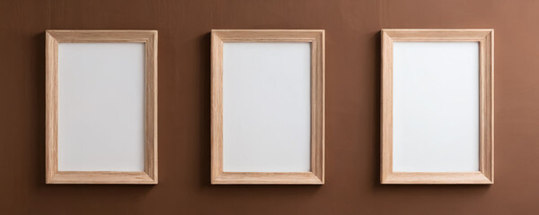 Three empty frames on a brown wall ready for artwork display in an interior space