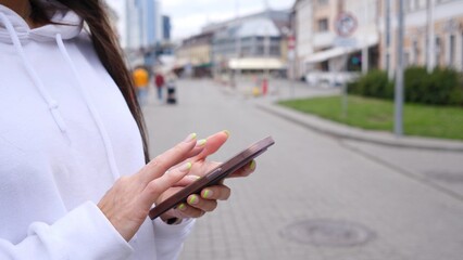 A closeup view captures a person casually texting on their smartphone while immersed in a lively...