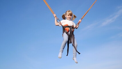A young girl swings joyfully in the air under a clear blue sky, embodying her carefree playfulness and innocence