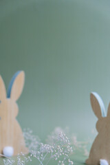Defocused background Wooden minimalism low-key bunny decor in pastel green background. Sustainable holiday minimalistic still life composition. Copy space template for invitation greeting card