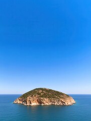 A tranquil island surrounded by clear blue waters and sky.