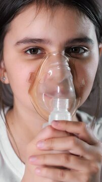 Little girl wearing a breathing medical mask. The girl does inhalation. Treatment of respiratory diseases. Little girl wearing a breathing medical mask. Vertical video.