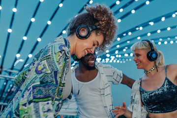 Friends enjoying music at silent disco festival under string lights
