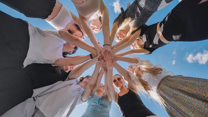 Circle of young individuals joining hands in the air