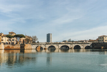 Naklejka premium anicent roman bridge from first century in rimini on clear sky with water refelction