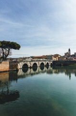 Obraz premium anicent roman bridge from first century in rimini on clear sky with water refelction