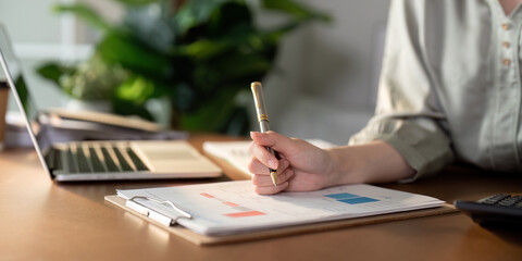 Woman analyzing financial documents while holding a pen, emphasizing financial planning.
