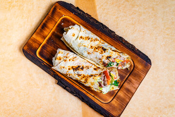 Delicious rolled wraps on wooden serving tray with fresh ingredients