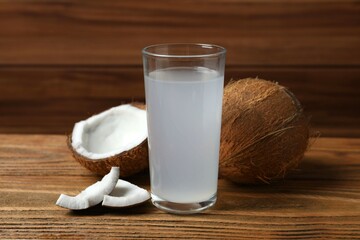 Glass with coconut water with nuts on wooden table