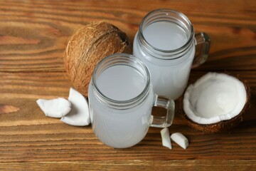 Mason jars with coconut water with nuts on wooden table