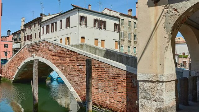 CHIOGGIA, ITALY - APRIL 19 2018: brick bridge Zitelle Vecchie over the Vena canal. Old buildings near the canal.