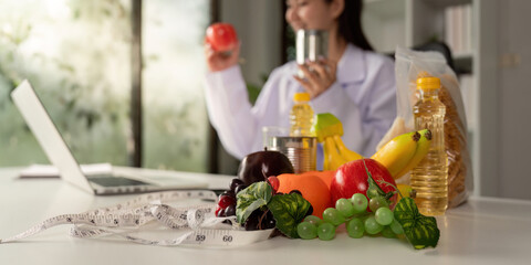 Nutritionist showcasing fruits and canned goods while holding an apple, promoting healthy lifestyle choices during a consultation.