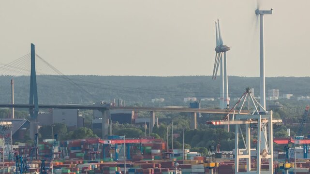 Aerial timelapse of Hamburg cargo port, showcasing container terminals, cranes and cargo ships on the Elbe River. Working wind power stations. Boats and vessels pass by, maritime panorama. Germany