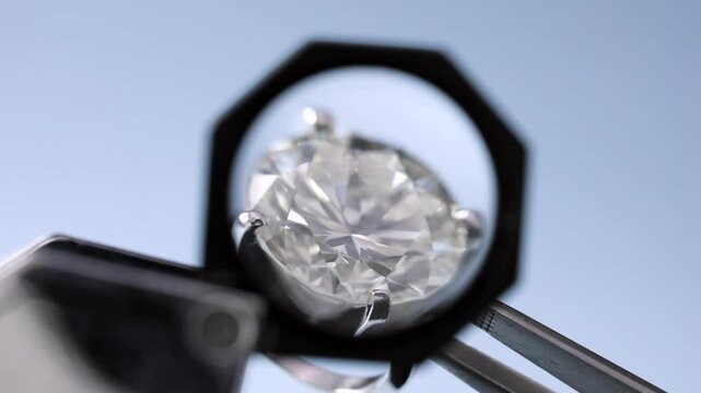 real brilliant round diamond ring is being held and looked through 10x loupe