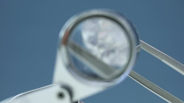 real loose round diamond with inclusions is being held and looked through 10x loupe